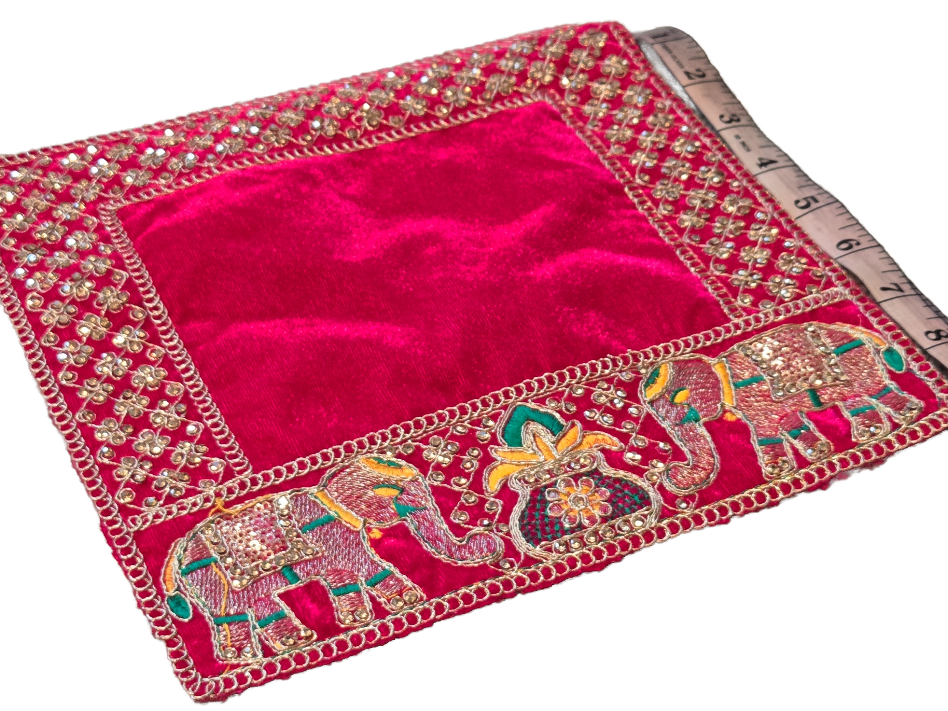 A square magenta/pink velvet fabric piece with an ornate gold embroidered border featuring elephant motifs and a ruler placed along one edge for scale, shown on a white background.