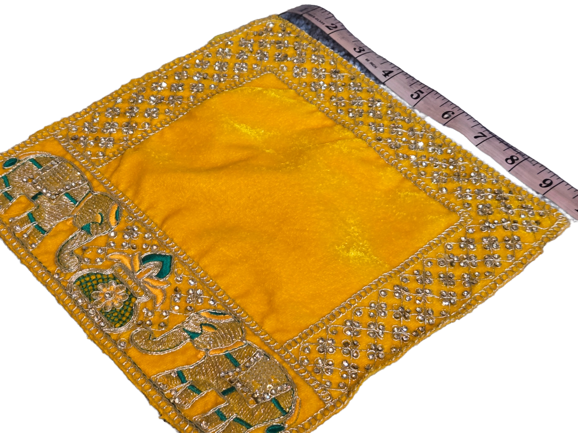 A square yellow fabric panel with a wide embroidered border, shown on a white background with a measuring tape placed along one edge for scale. The border features metallic gold embroidery, small silver rhinestone-like embellishments, and green decorative details.